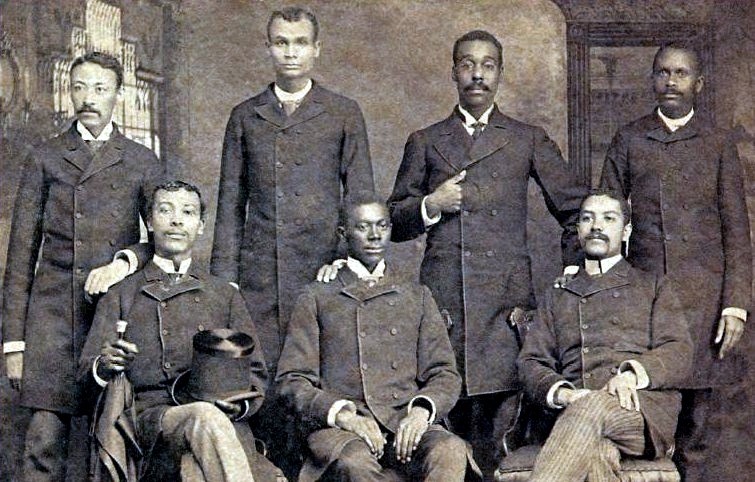 Image shows seven Black men posing for their medical school graduation photo