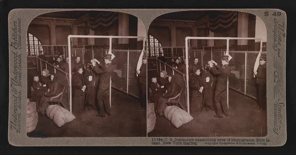 Image shows U.S. inspectors examining eyes of immigrants at Ellis Island, New York 