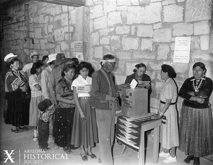 Image shows Navajo people lined up to cast their vote at a ballot box for the 1955 Tribal Election 