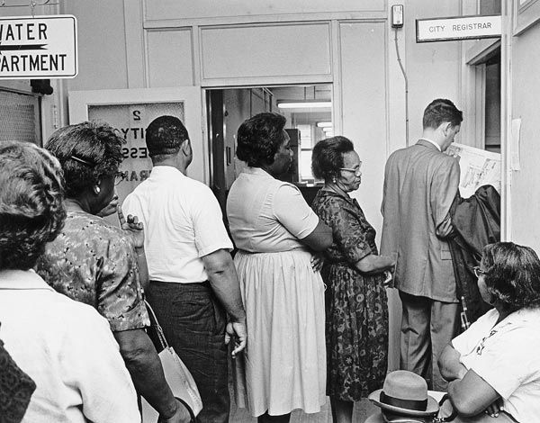 Image shows people waiting in line to register to vote in Virginia