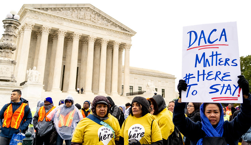 Image shows protestors holding signs outside the Supreme Court as the DACA cases are heard inside