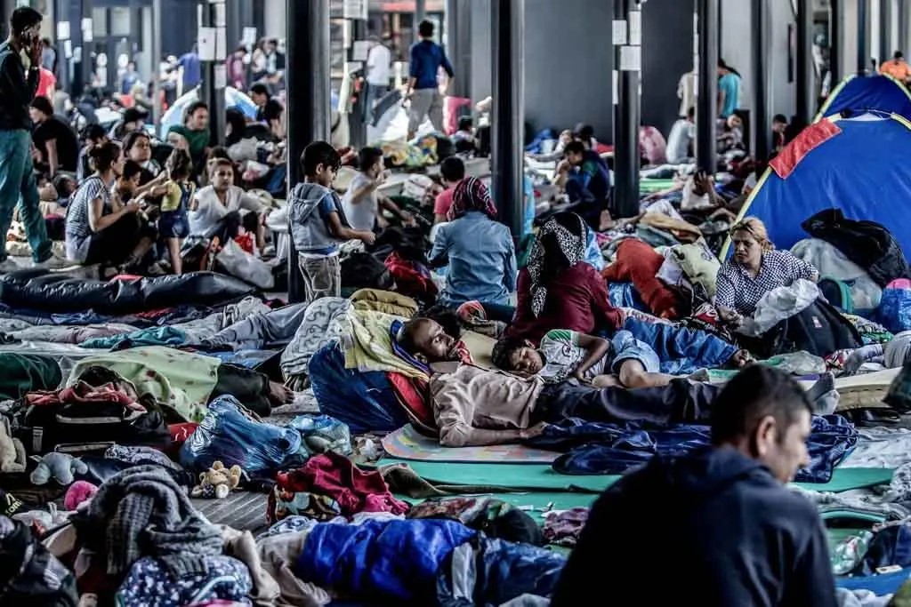 Image shows a crowd of men, women and children waiting at the U.S. border seeking asylum
