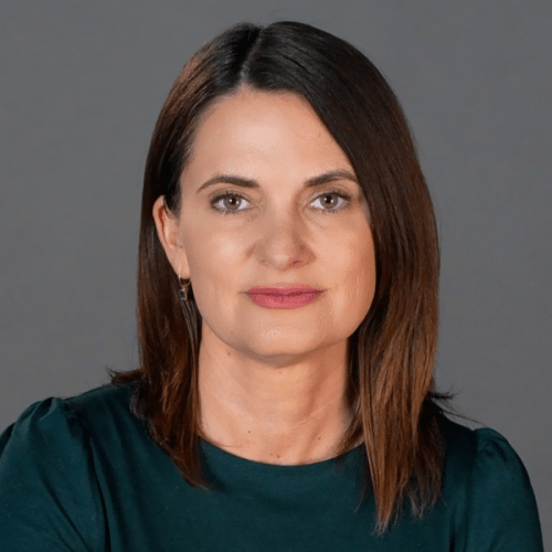 Professional photo of Cynthia Cox in a forest green top against a gray background.
