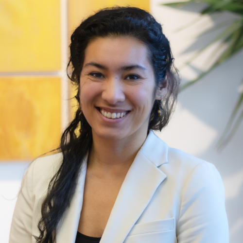 Professional photo of Hayat Norimine in a white blazer against a wall with a yellow painting.