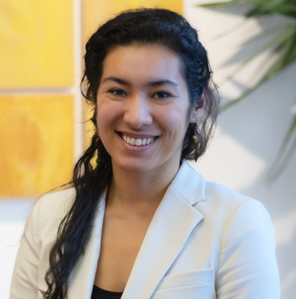 Professional photo of Hayat Norimine in a white blazer against a wall with a yellow painting.