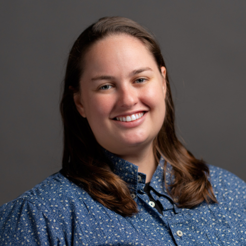 Professional headshot photo of Taylor Cook smiling wearing a blue buttoned shirt with a white leafy pattern.